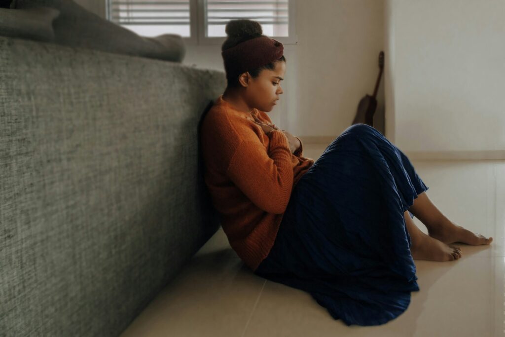 Person sitting on the floor holding their chest, experiencing anxiety and seeking calm at home.
